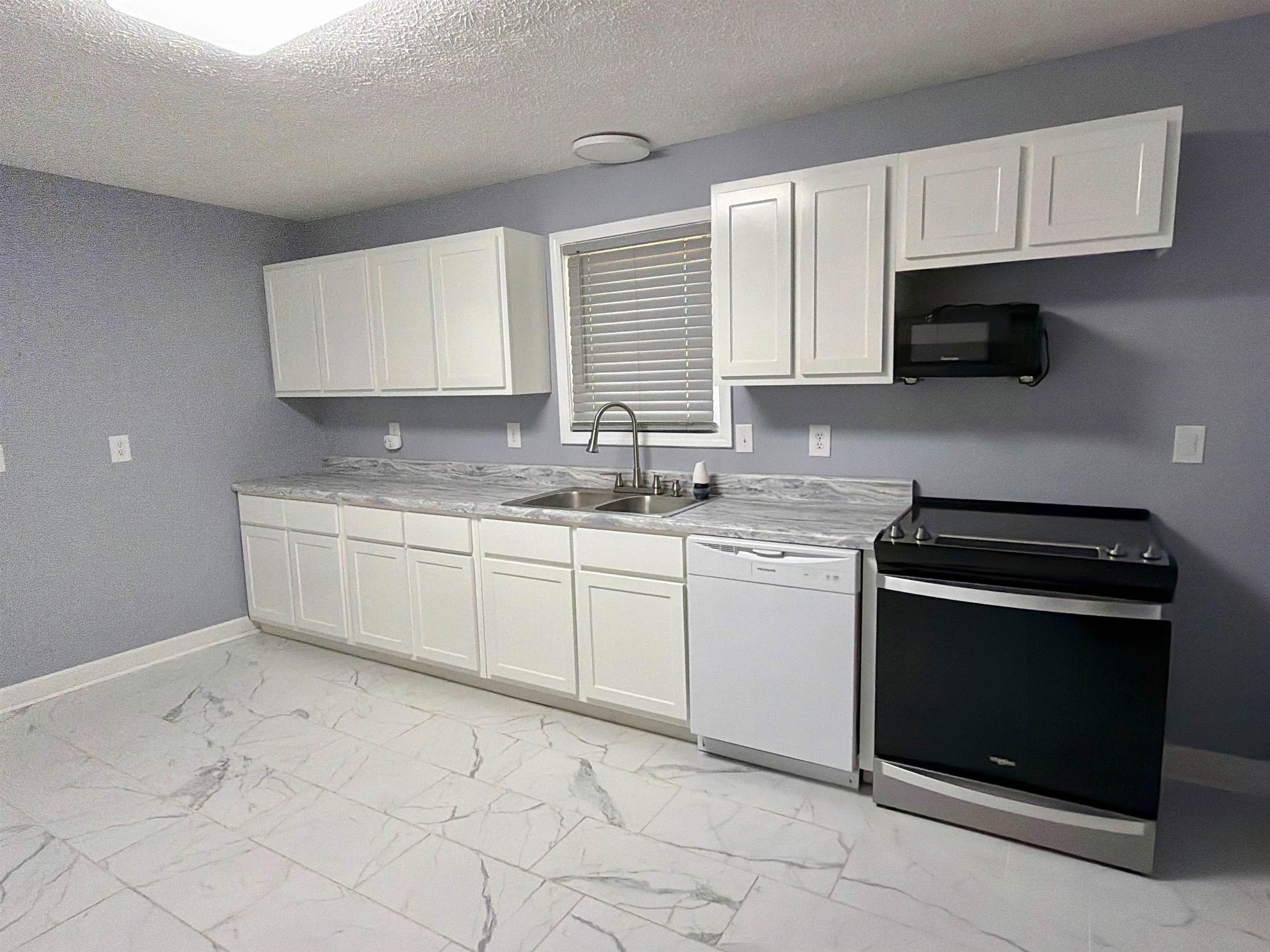 8022 45th Highway Ramer, TN 38367 - Photo 6 of 21 White cabinetry, coordinating countertops, stainless steel sink, built-in microwave, and tile flooring