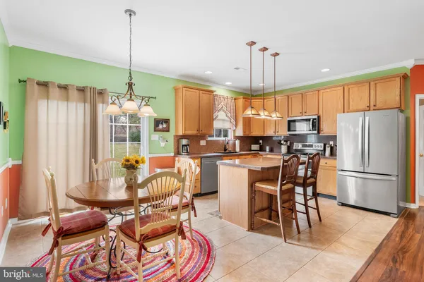 a kitchen with stainless steel appliances kitchen island granite countertop a refrigerator a stove a kitchen island a dining table and chairs