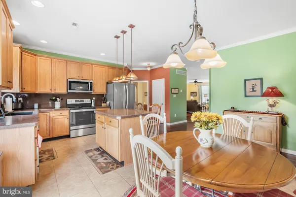 a kitchen with stainless steel appliances kitchen island granite countertop a refrigerator a stove top oven a sink dishwasher and a dining table with wooden floor