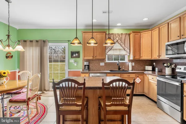a kitchen with stainless steel appliances granite countertop a stove a sink a dining table and chairs