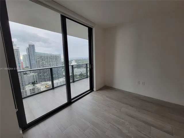 an empty room with wooden floor and a balcony