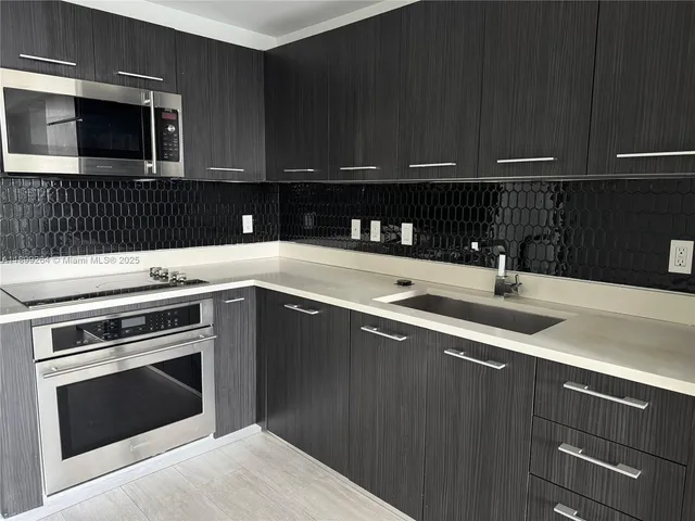 a kitchen with a sink and steel appliances