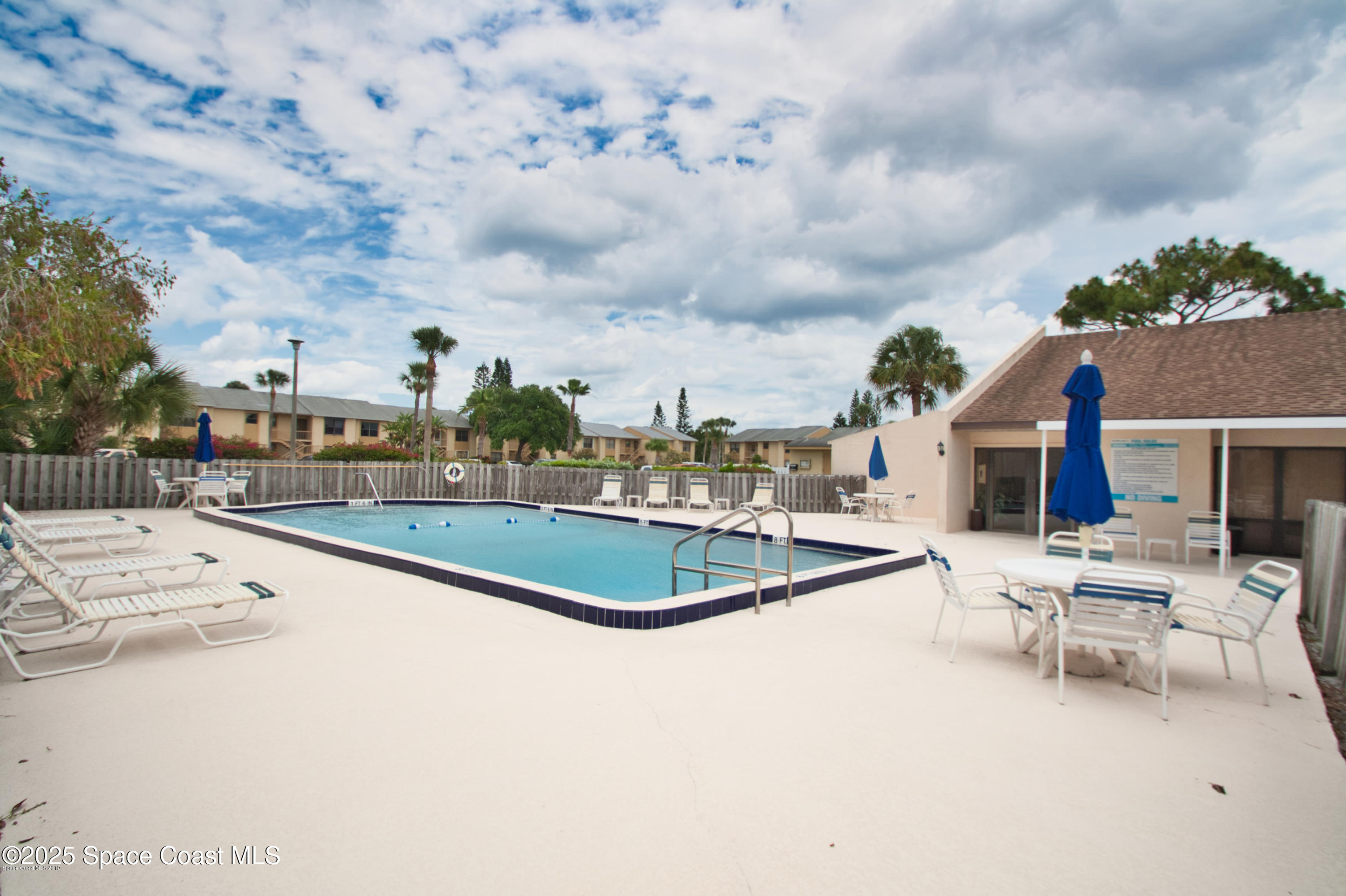 2550 Eagle Drive, Unit 3C Melbourne, FL 32935 - Photo 14 of 14 a view of a swimming pool with lawn chairs and wooden fence