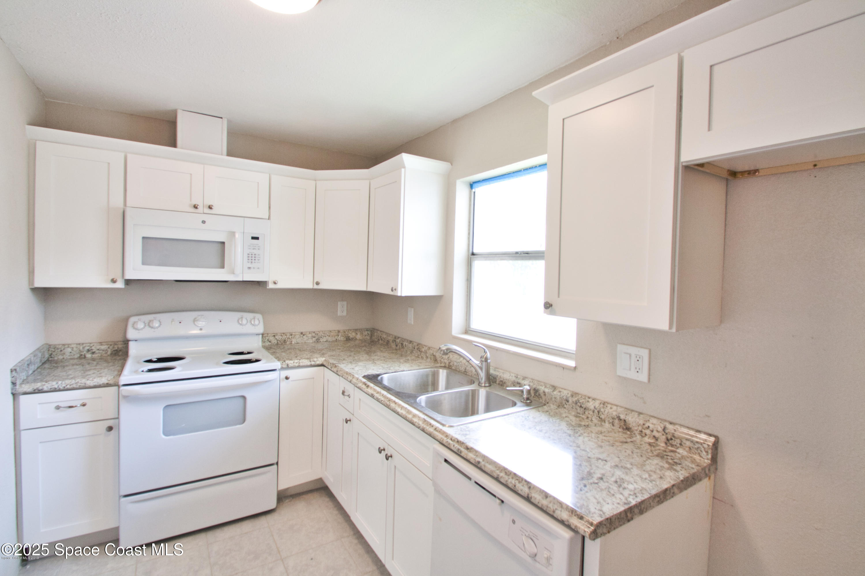 2550 Eagle Drive, Unit 3C Melbourne, FL 32935 - Photo 2 of 14 a kitchen with cabinets appliances a sink and a window