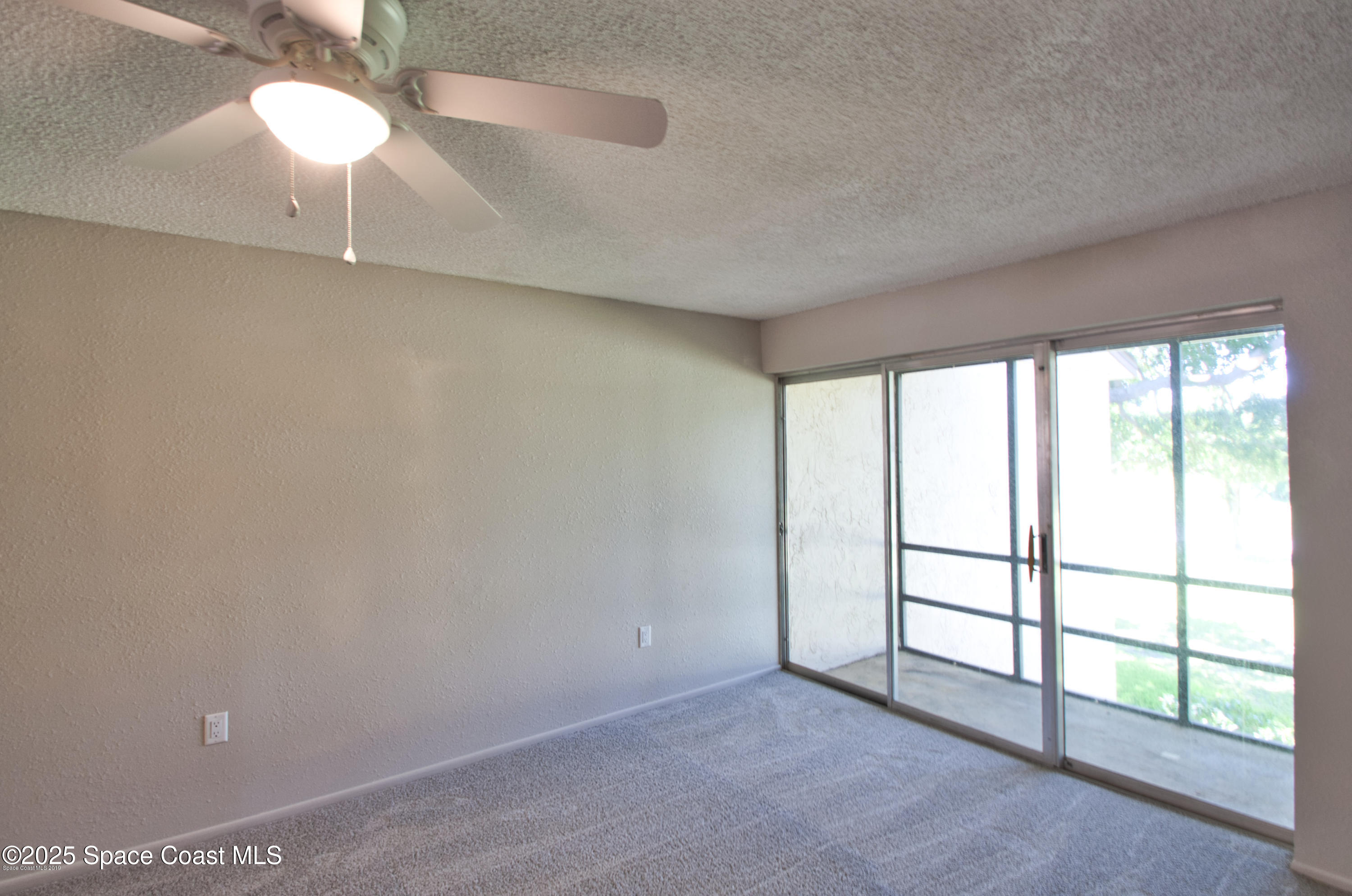 2550 Eagle Drive, Unit 3C Melbourne, FL 32935 - Photo 4 of 14 an empty room with a chandelier fan and windows