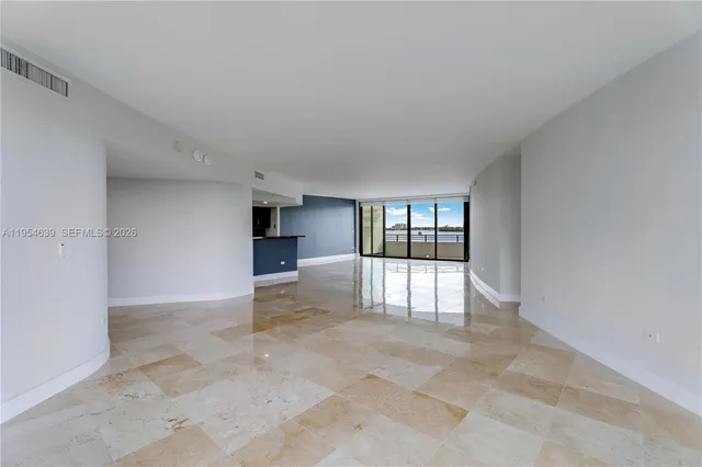 an empty room with floor to ceiling window and kitchen
