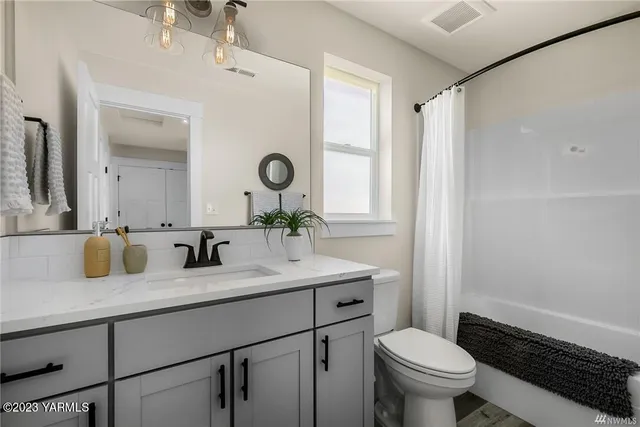 a bathroom with a granite countertop sink mirror vanity and toilet