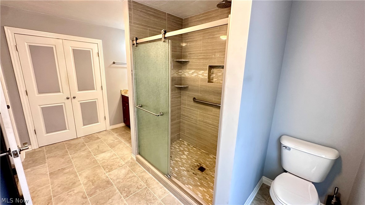2603 Rockefeller Road Wickliffe, OH 44092 - Photo 13 of 34 Spacious bathroom featuring a glass-enclosed shower with tile surround, built-in shelving, and a rain showerhead