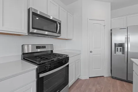 a kitchen with stainless steel appliances granite countertop a stove a microwave and a refrigerator