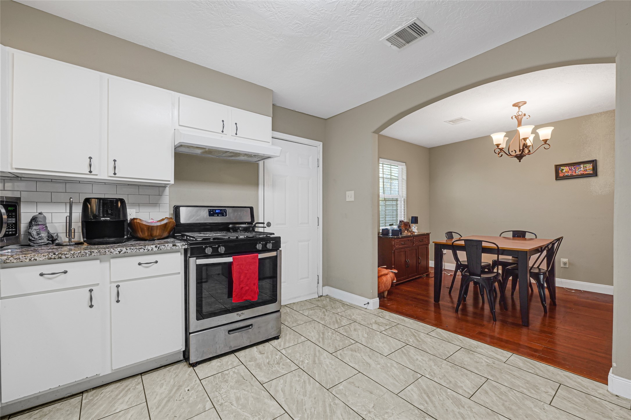 4529 Perry Street Houston, TX 77021 - Photo 8 of 20 a kitchen with stainless steel appliances granite countertop a stove top oven a sink a dining table and chairs with white cabinets