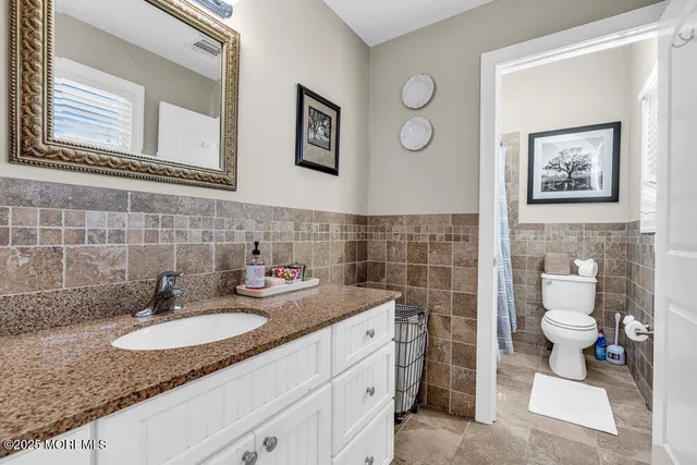 a bathroom with a granite countertop sink a toilet and a mirror