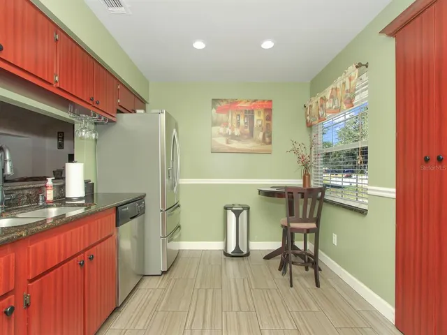 a kitchen with stainless steel appliances granite countertop a refrigerator a sink and wooden cabinets