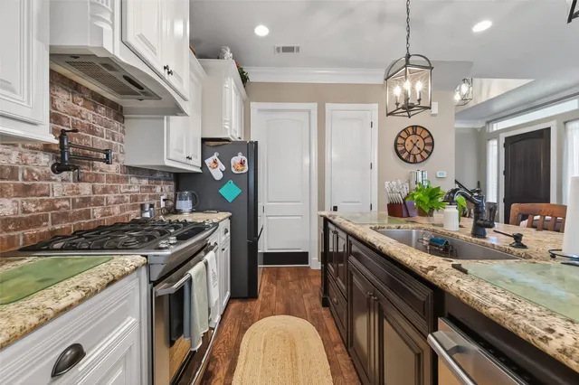 a kitchen with stainless steel appliances granite countertop a stove a sink and a wooden cabinets