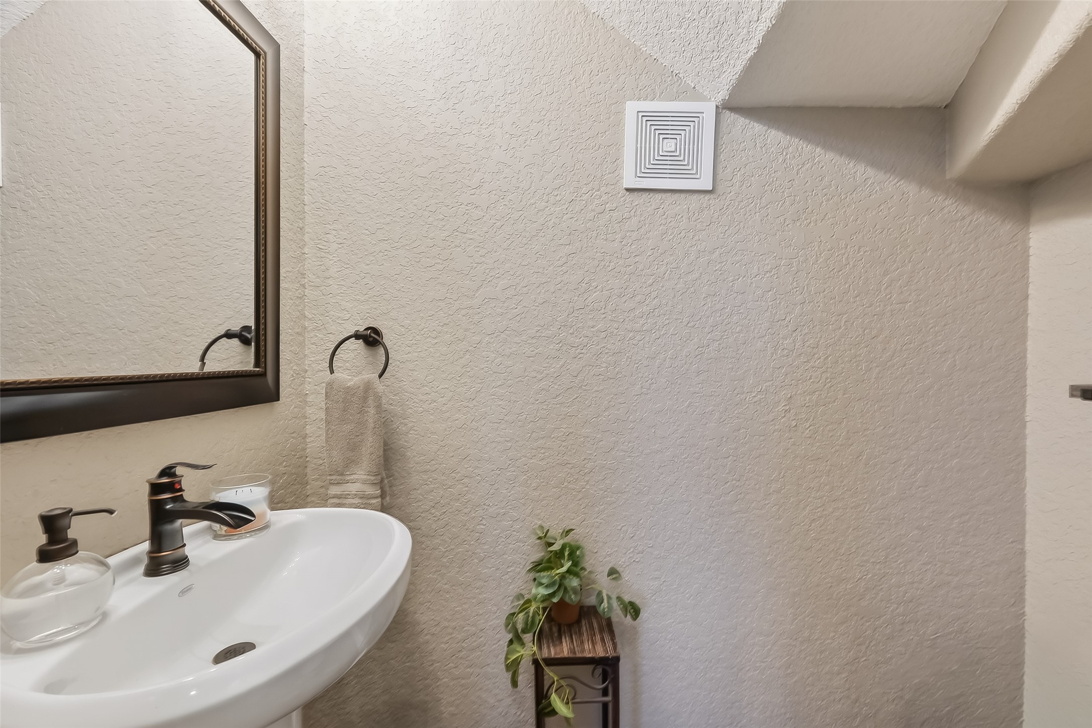 912 County Road 340 Angleton, TX 77515 - Photo 19 of 50 This photo shows a compact powder room with a pedestal sink, a stylish faucet, and a large framed mirror. The space features neutral tones and a towel ring.