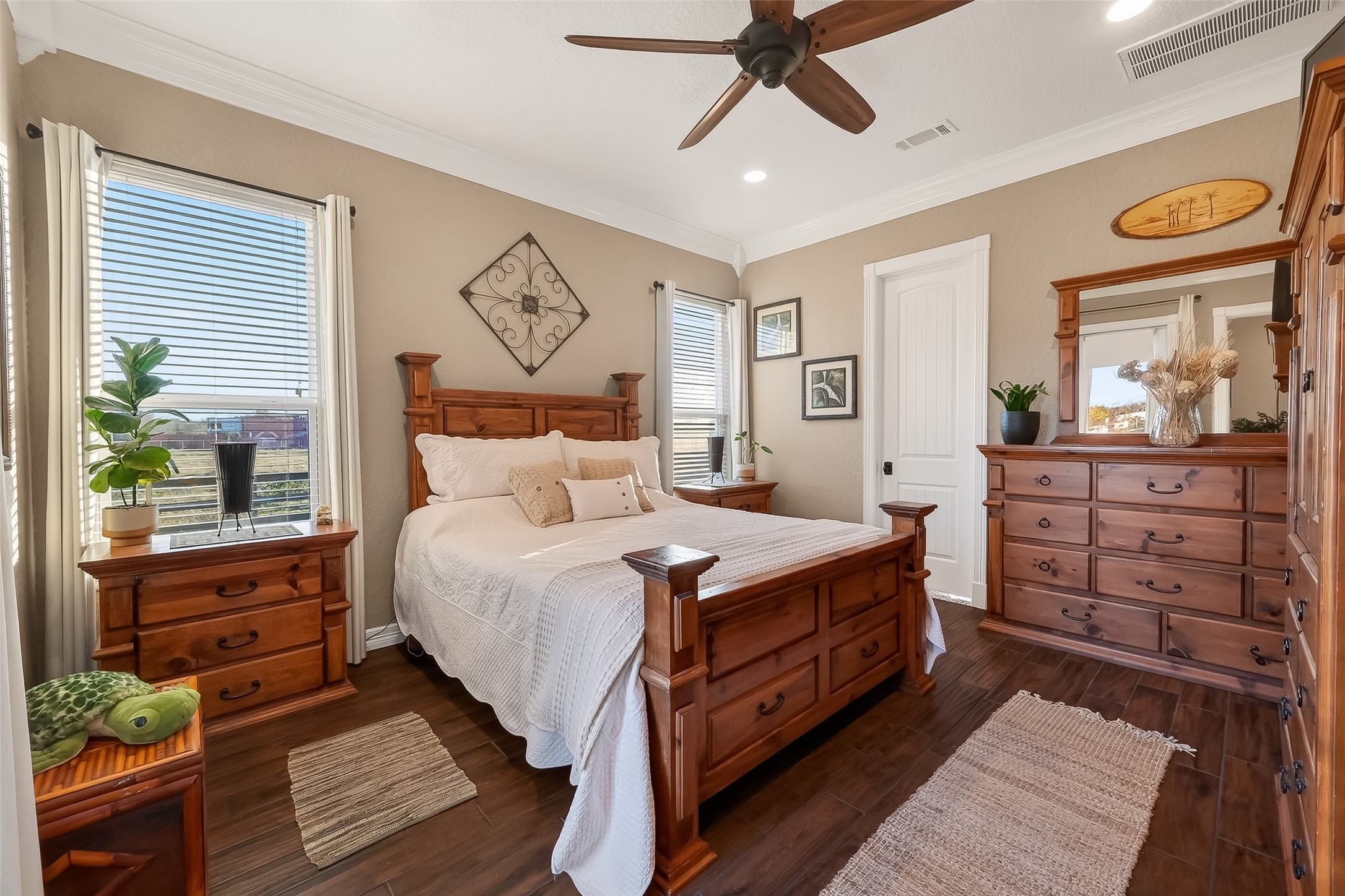 912 County Road 340 Angleton, TX 77515 - Photo 27 of 50 Cozy primary bedroom with warm feel. The room features two large windows allowing natural light, hardwood floors, and a ceiling fan.