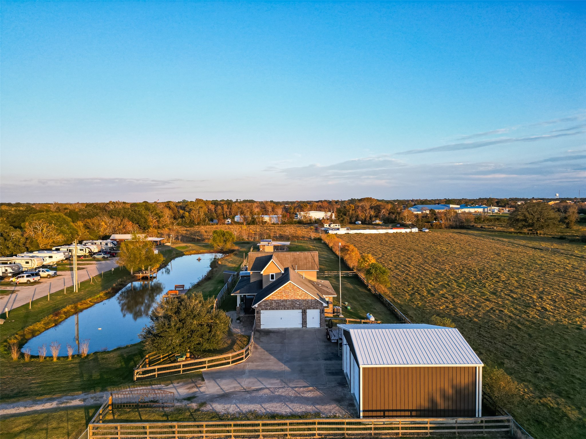 912 County Road 340 Angleton, TX 77515 - Photo 36 of 50 This property features a charming home with a spacious driveway and garage, situated on a large plot with open fields. A scenic pond and fenced areas enhance the rural appeal, offering a serene country living experience.