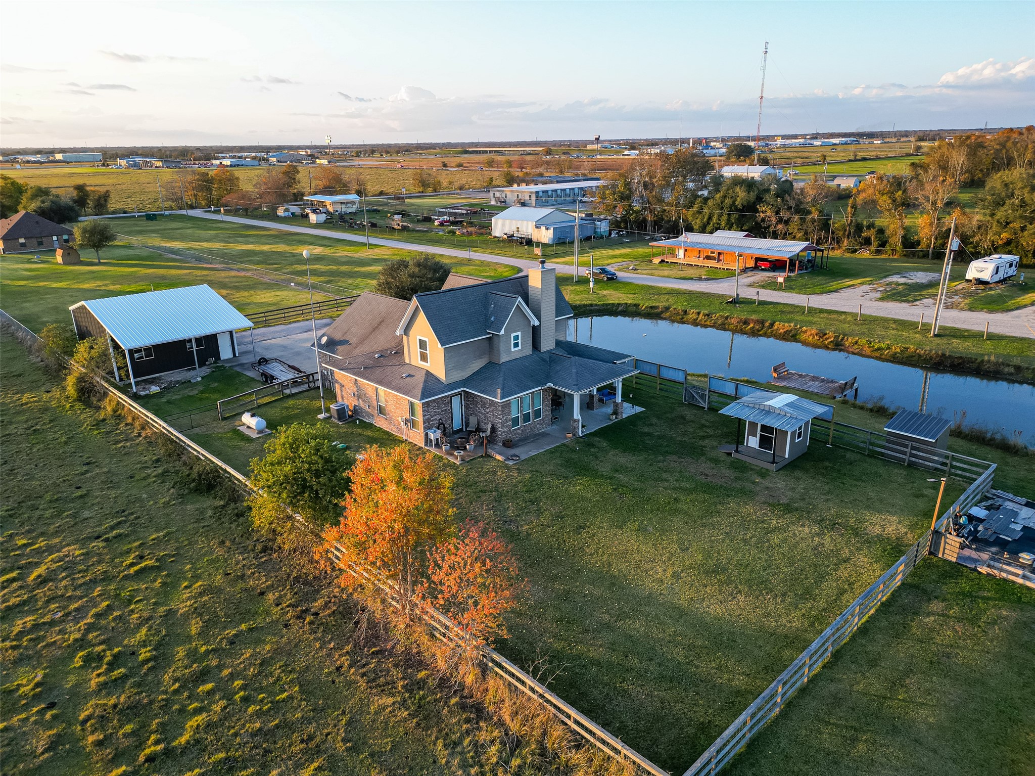 912 County Road 340 Angleton, TX 77515 - Photo 39 of 50 Charming two-story home on a spacious lot with a large yard. Features a waterfront view with a nearby pond, a detached garage, and a covered patio. Surrounded by open fields, providing a peaceful, rural setting.