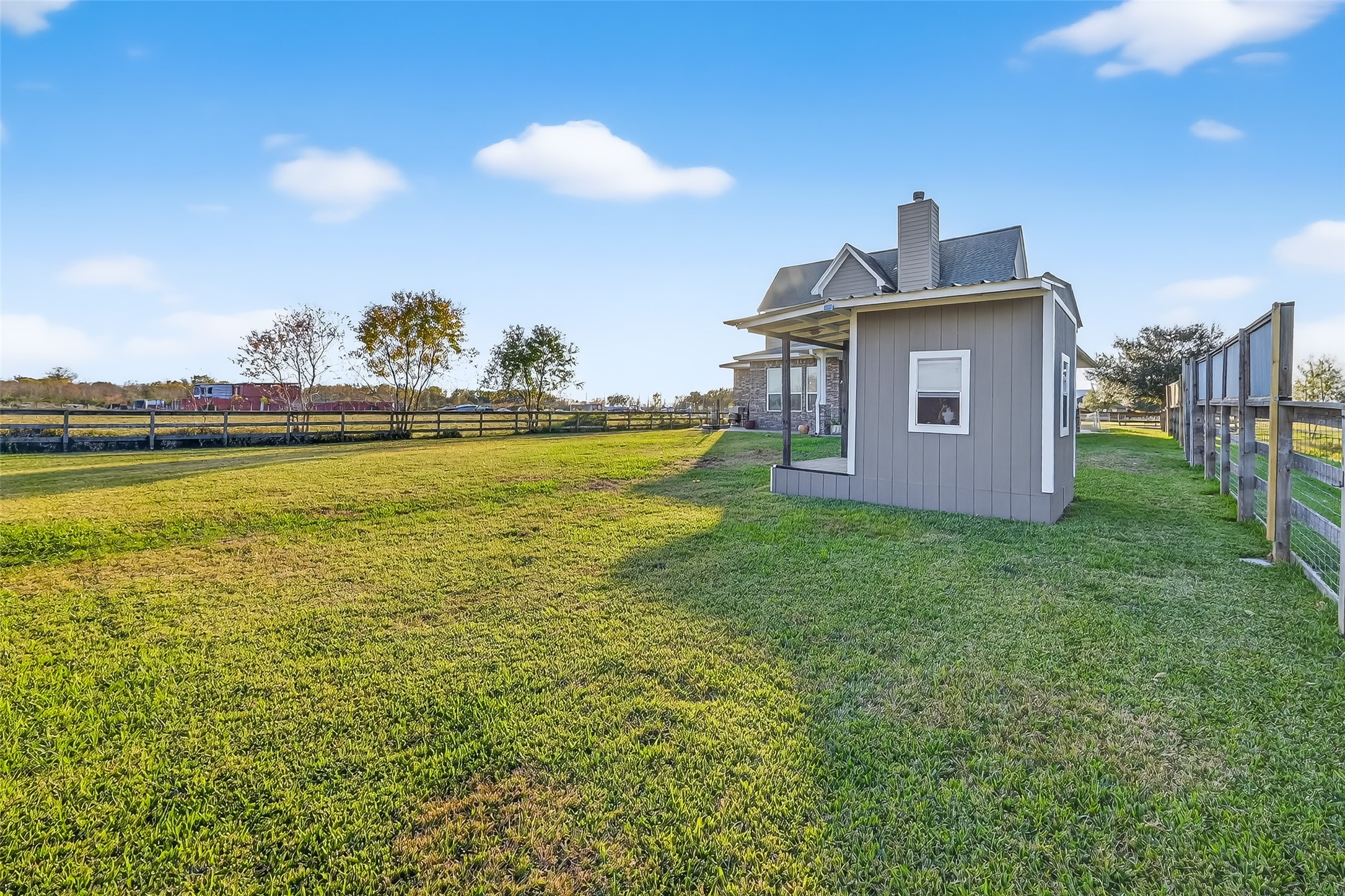 912 County Road 340 Angleton, TX 77515 - Photo 40 of 50 Charming rural property featuring a cozy dog house with a spacious yard, surrounded by open fields and a wooden fence. Ideal for those seeking tranquility and scenic views.