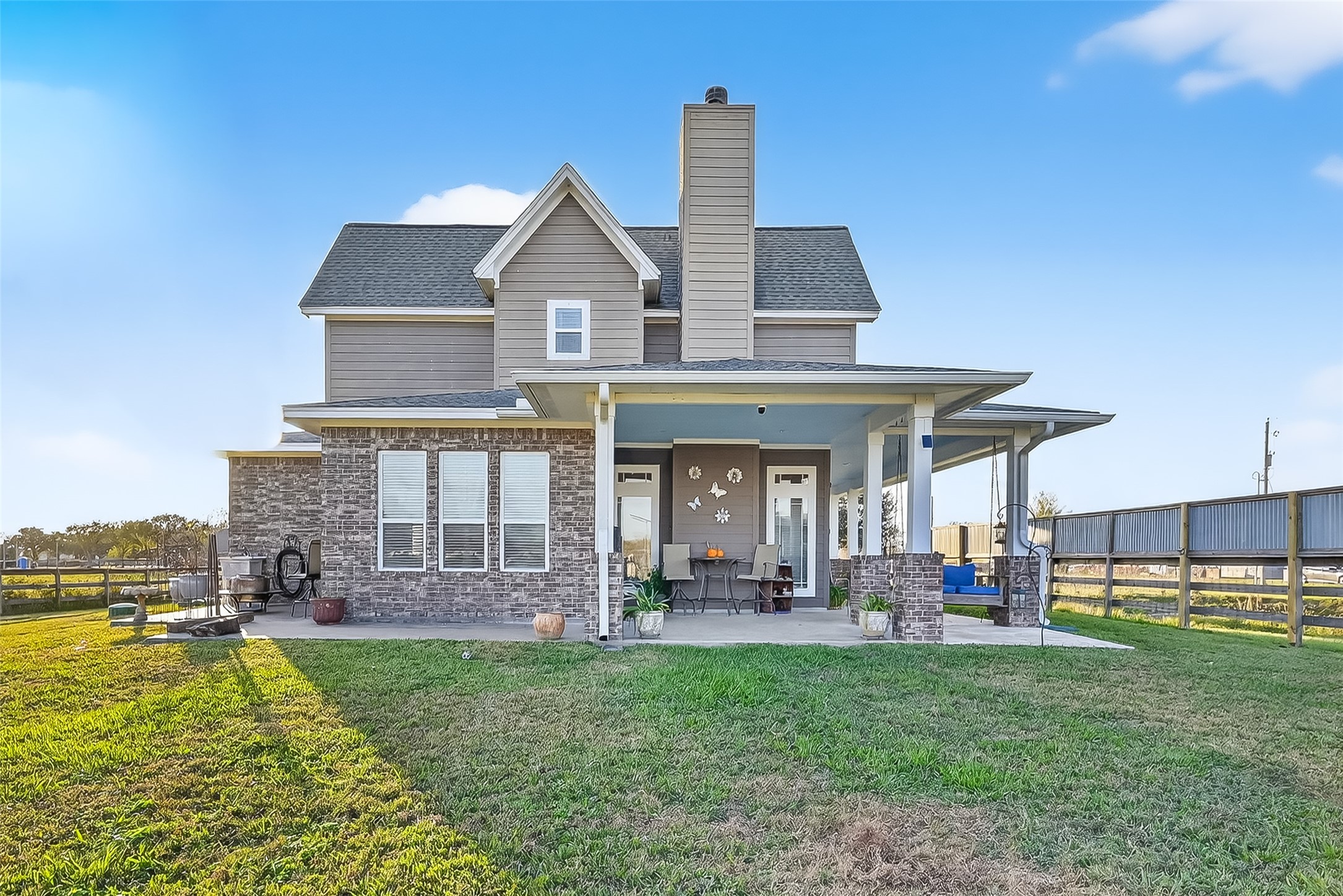 912 County Road 340 Angleton, TX 77515 - Photo 5 of 50 This photo showcases a charming two-story home with a mix of brick and siding exterior. It features a spacious covered patio perfect for outdoor relaxation. The property is surrounded by a large, fenced yard, ideal for enjoying open space and privacy.