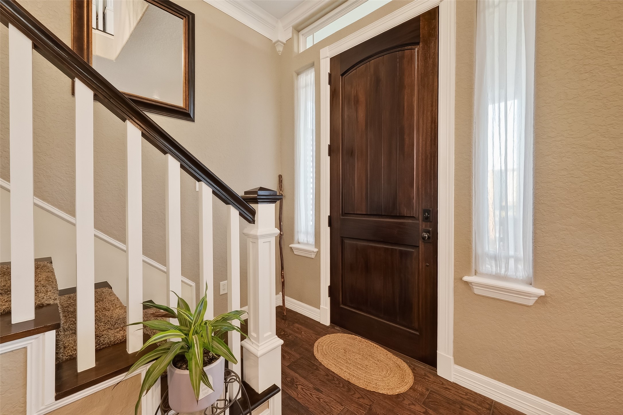 912 County Road 340 Angleton, TX 77515 - Photo 8 of 50 This welcoming entryway features a rich wooden front door, natural light from side windows, and a staircase with elegant white railings. The space is complemented by a warm color palette, creating a cozy and inviting atmosphere.