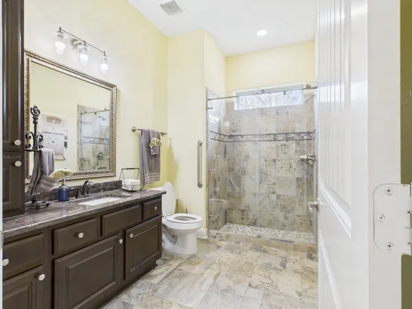 a bathroom with a double vanity sink toilet mirror and shower