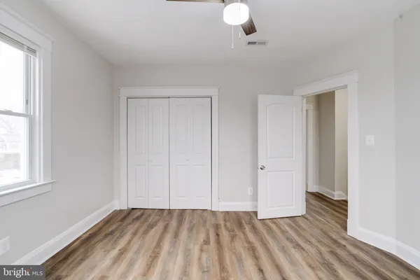 an empty room with wooden floor cabinet and windows