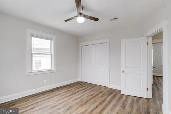 an empty room with wooden floor chandelier fan and windows