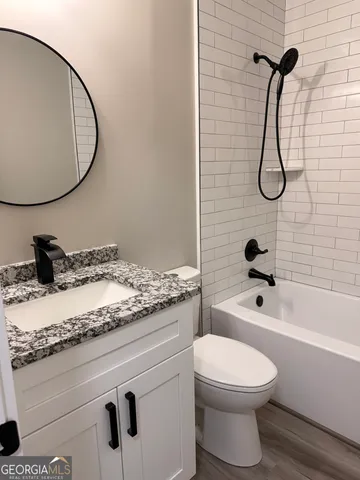 a bathroom with a granite countertop toilet sink and mirror
