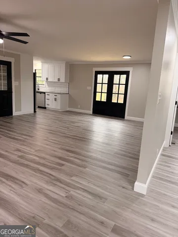 a view of kitchen and empty room with wooden floor