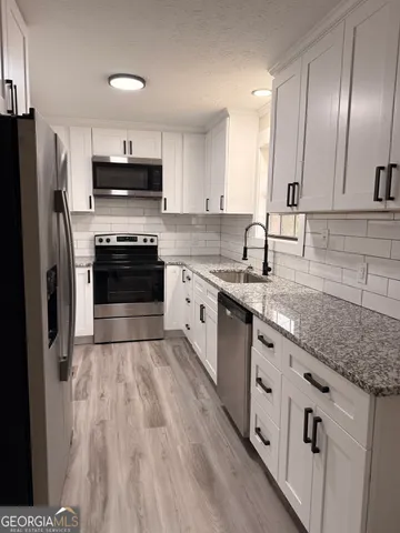 a kitchen with stainless steel appliances granite countertop a sink a stove a refrigerator and cabinets