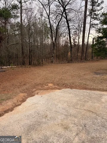 a view of dirt yard with trees