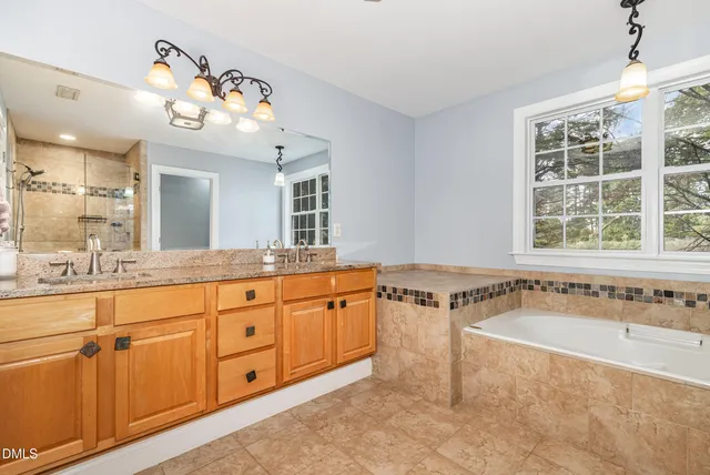 a spacious bathroom with a tub sink and mirror