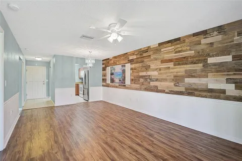 a view of an empty room with wooden floor and a kitchen