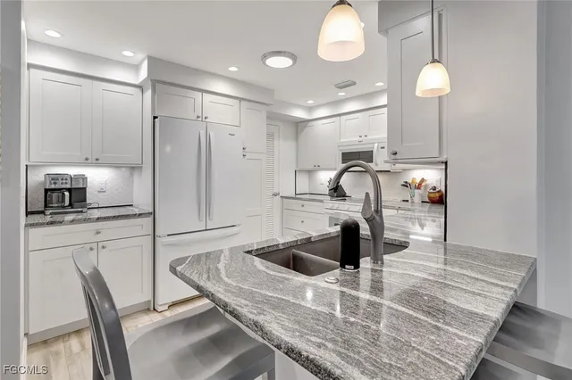 a kitchen with stainless steel appliances granite countertop a sink refrigerator and cabinets