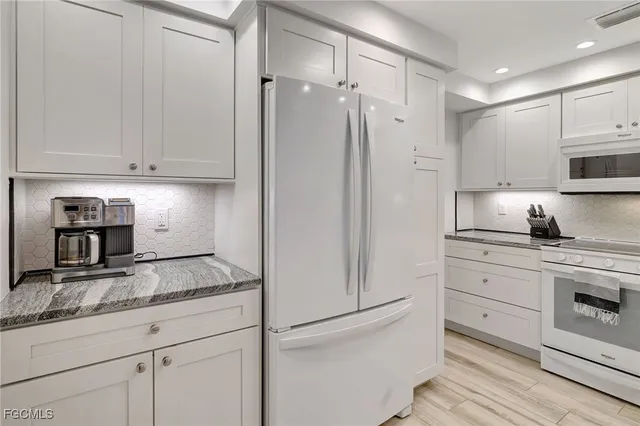 a kitchen with granite countertop white cabinets and white appliances