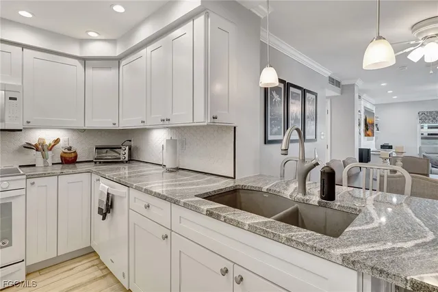 a kitchen with white cabinets and sink