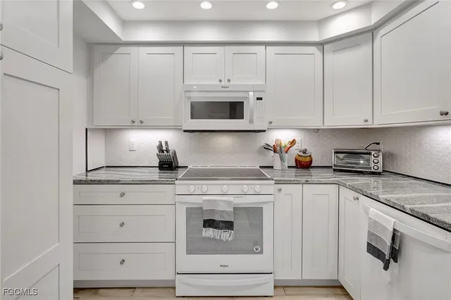 a kitchen with granite countertop white cabinets white stainless steel appliances and a sink