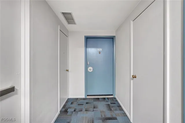 a view of a hallway with wooden floor and a bathroom
