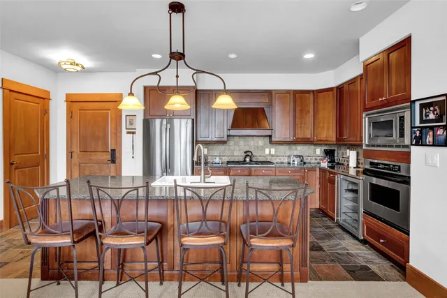 a kitchen with stainless steel appliances granite countertop a stove top oven a kitchen island a table and chairs
