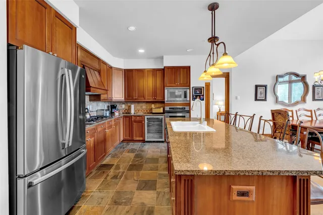 a kitchen with stainless steel appliances granite countertop a refrigerator a stove and a sink