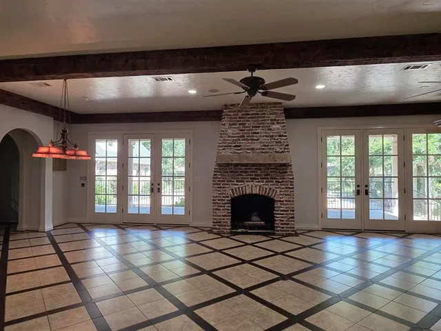 a view of an empty room with chandelier fan and fire place