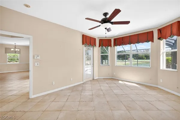 an empty room with windows and ceiling fan