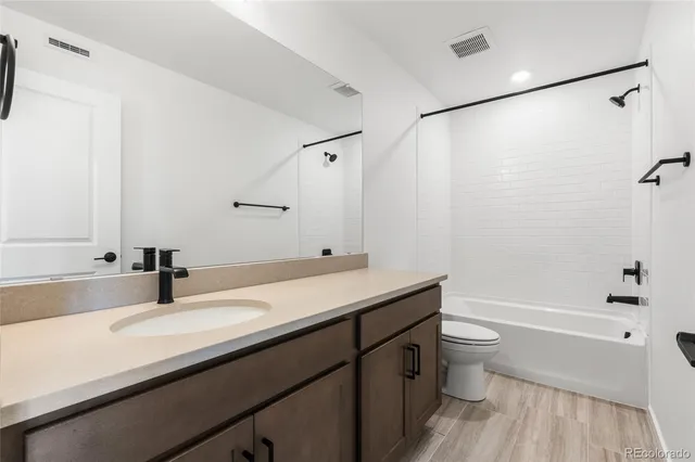 a bathroom with a granite countertop sink a toilet and shower