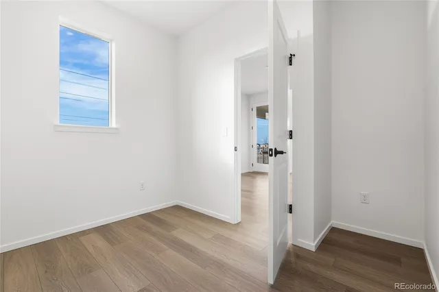 an empty room with wooden floor and entrance