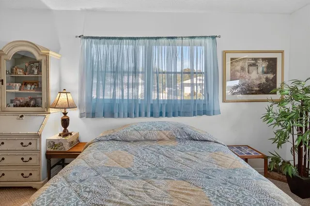 a bedroom with a bed and a potted plant on the dresser