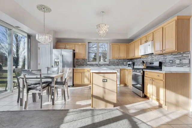 a kitchen with stainless steel appliances granite countertop a stove top oven a refrigerator a sink and a dining table with wooden floor