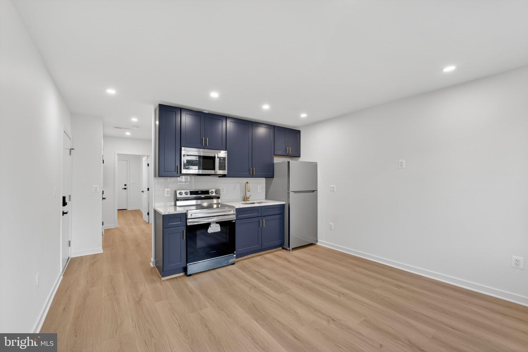 412 Newcomb Street Southeast Washington, DC 20032 - Photo 3 of 34 a large kitchen with stainless steel appliances granite countertop a stove a refrigerator a sink a microwave and white cabinets with wooden floor