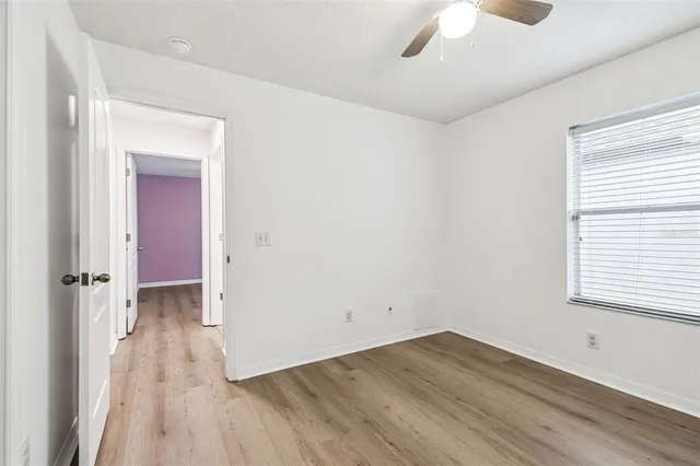 an empty room with wooden floor closet and windows