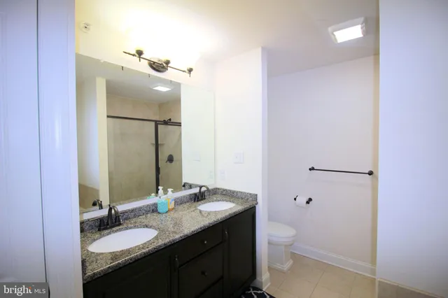 a bathroom with a granite countertop sink toilet and mirror