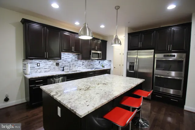 a kitchen with stainless steel appliances kitchen island granite countertop a refrigerator and a stove top oven